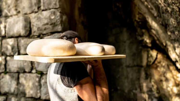 Käser trägt Käselaibe in den Reifungskeller.